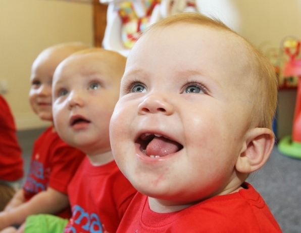 Nine month old baby boy in a red Pyjama Drama t-shirt, smiling showing two teeth
